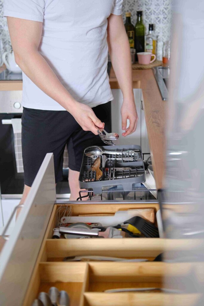 man takes out clean cutlery from dishwasher 11zon